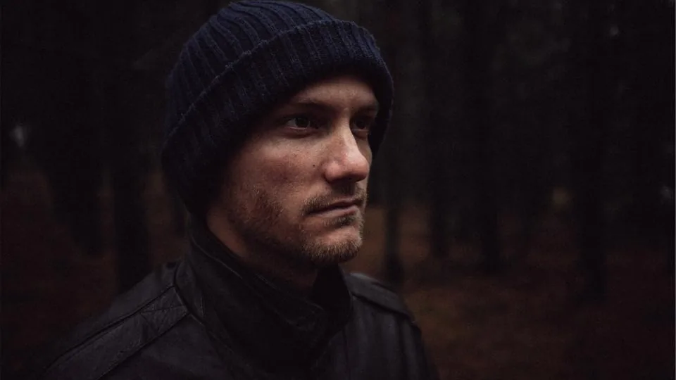 Retrato de homem em ambiente externo, com o rosto de perfil e pouca luz