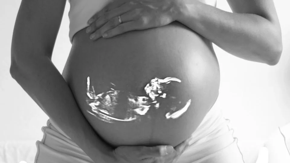 Barriga de gestante em primeiro plano, em fotografia preto e branco